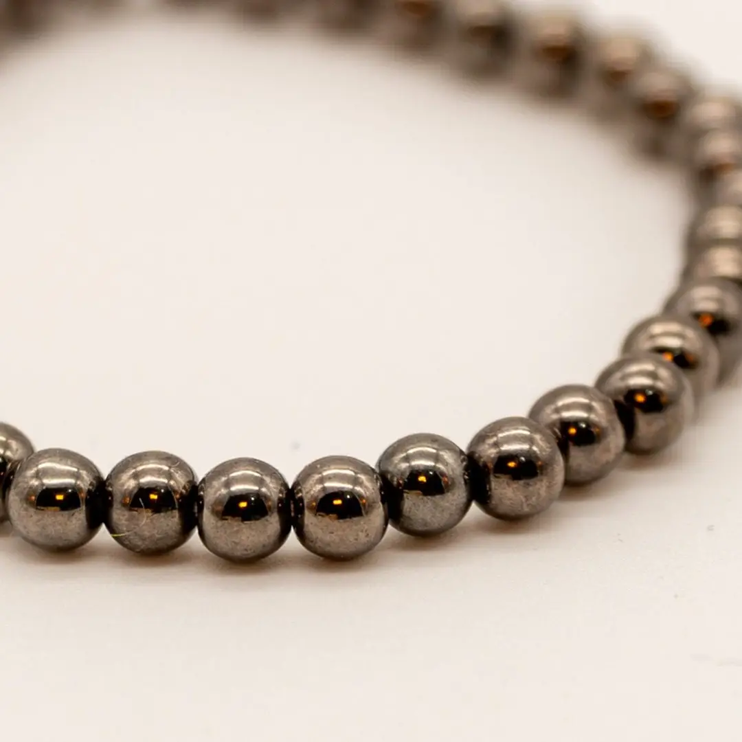 Pormenor da Pulseira Aço Fumado — Contas pequenas metálicas cinza-escuro (tipo hematite/aço), fio elástico