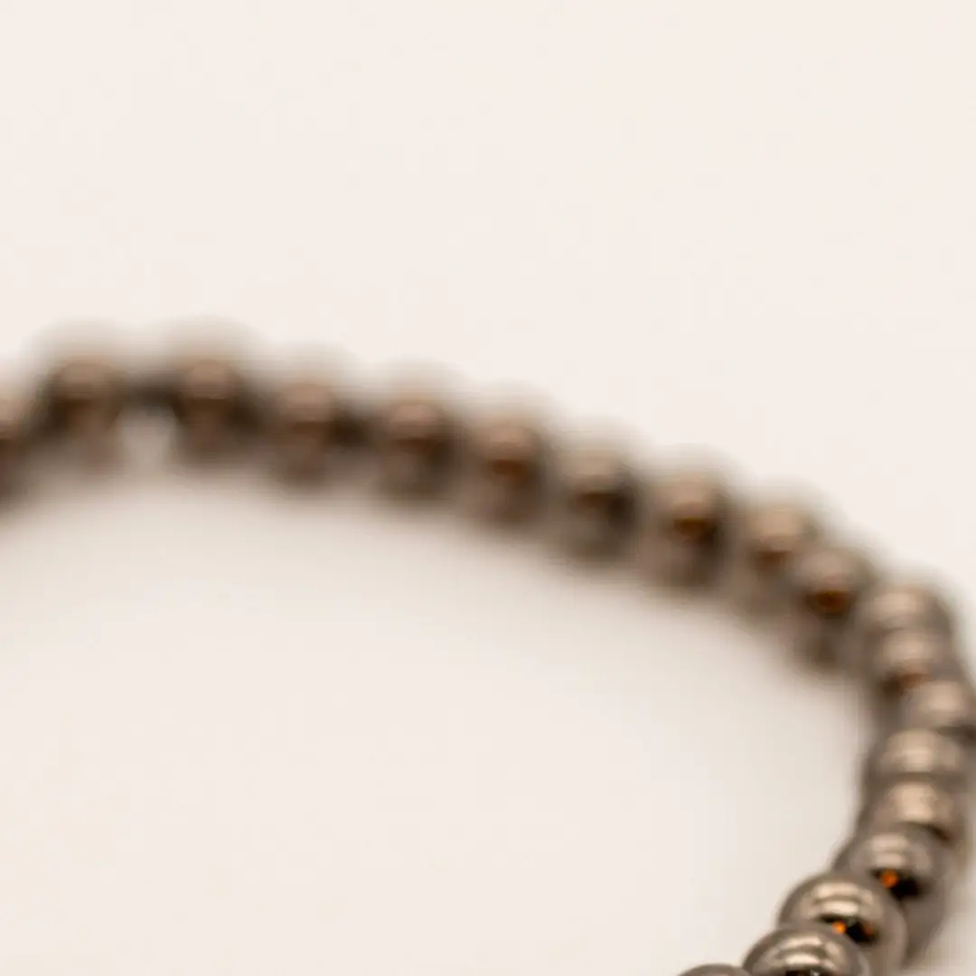 Pormenor da Pulseira Aço Fumado — Contas pequenas metálicas cinza-escuro (tipo hematite/aço), fio elástico